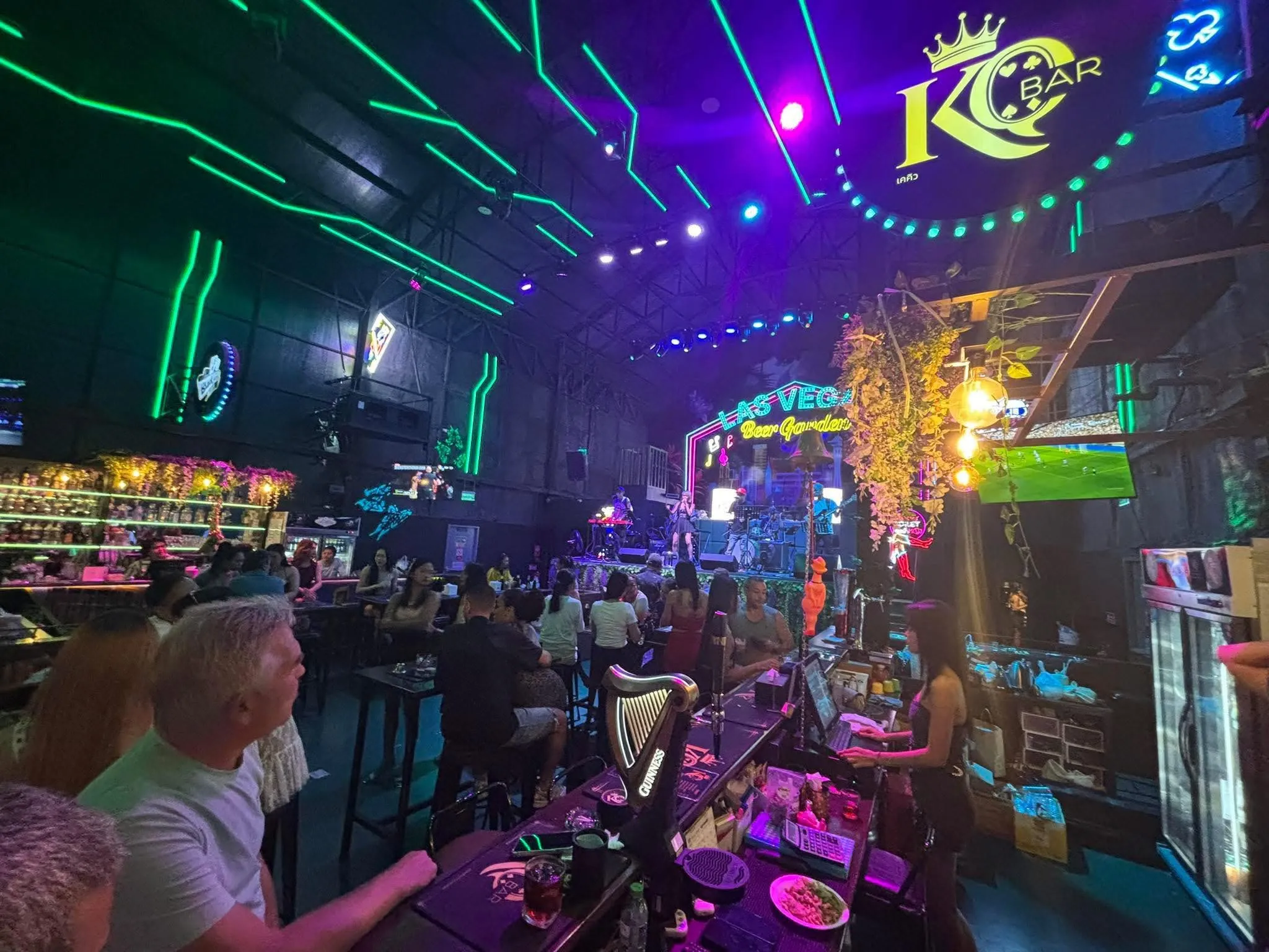 The KQ Bar counter with the Guinness tap in front, the crowd at the tables, and the band on the stage beyond